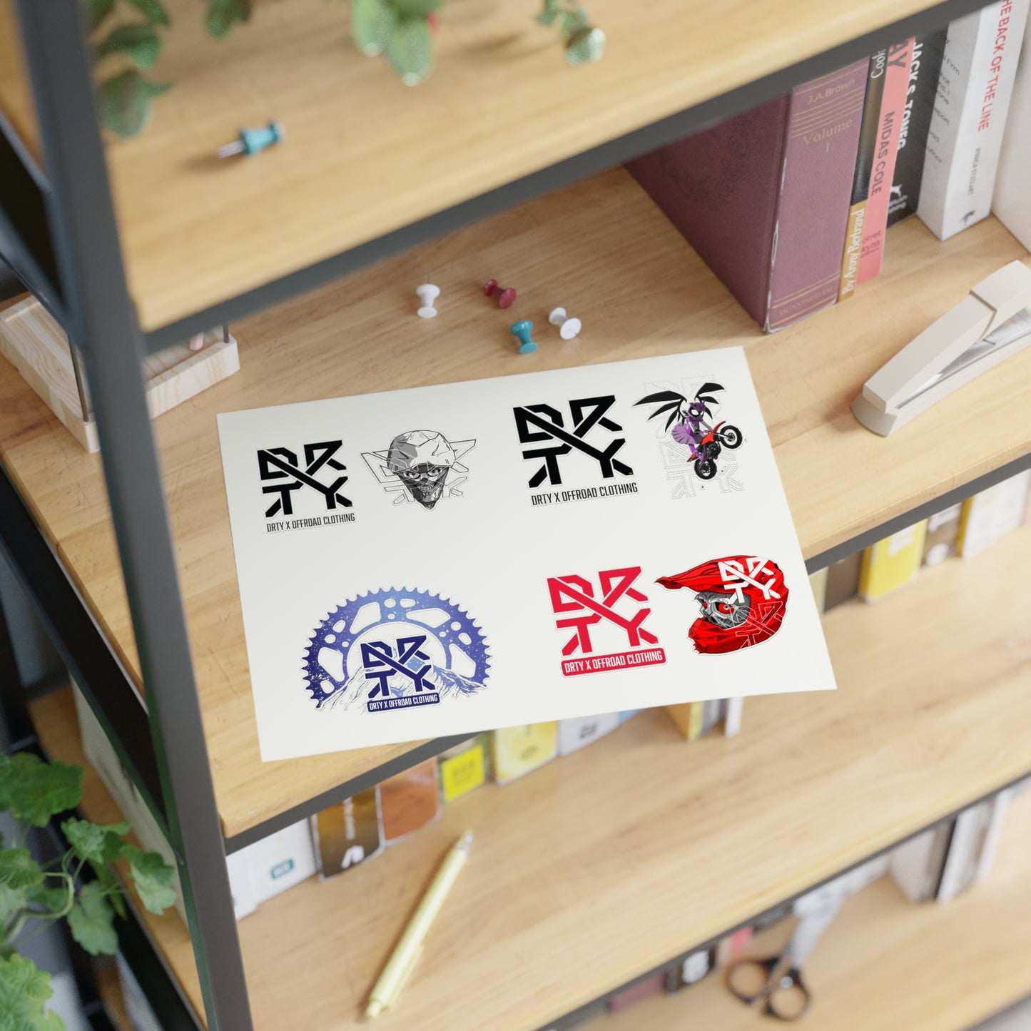 This image shows DRTY X logo and artwork sticker sheet on a bookshelf.