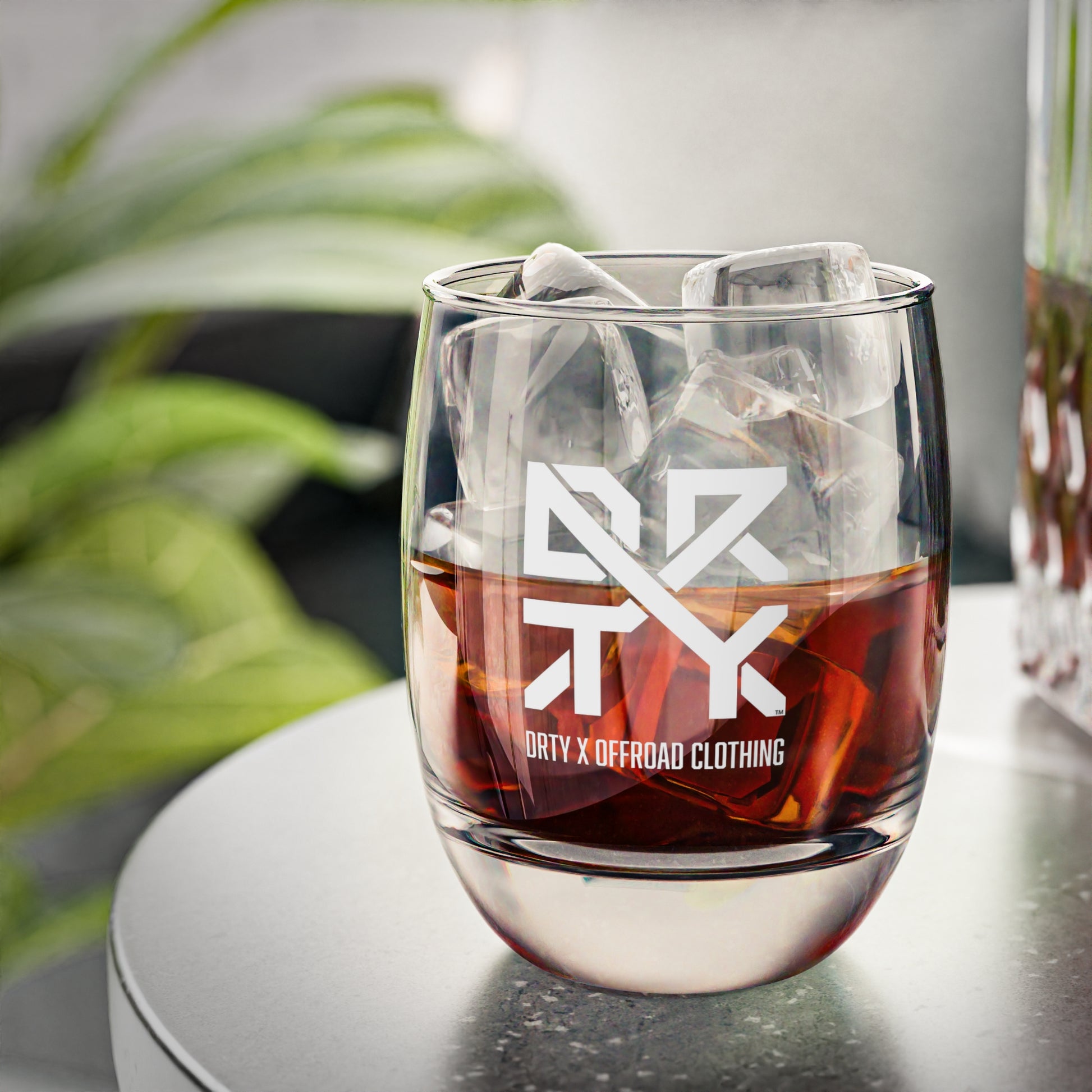 This image showcases a DRTY X branded whiskey glass on a table.