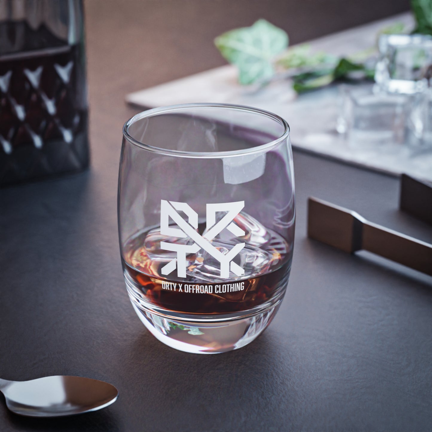 This image showcases a DRTY X branded whiskey glass on a table.