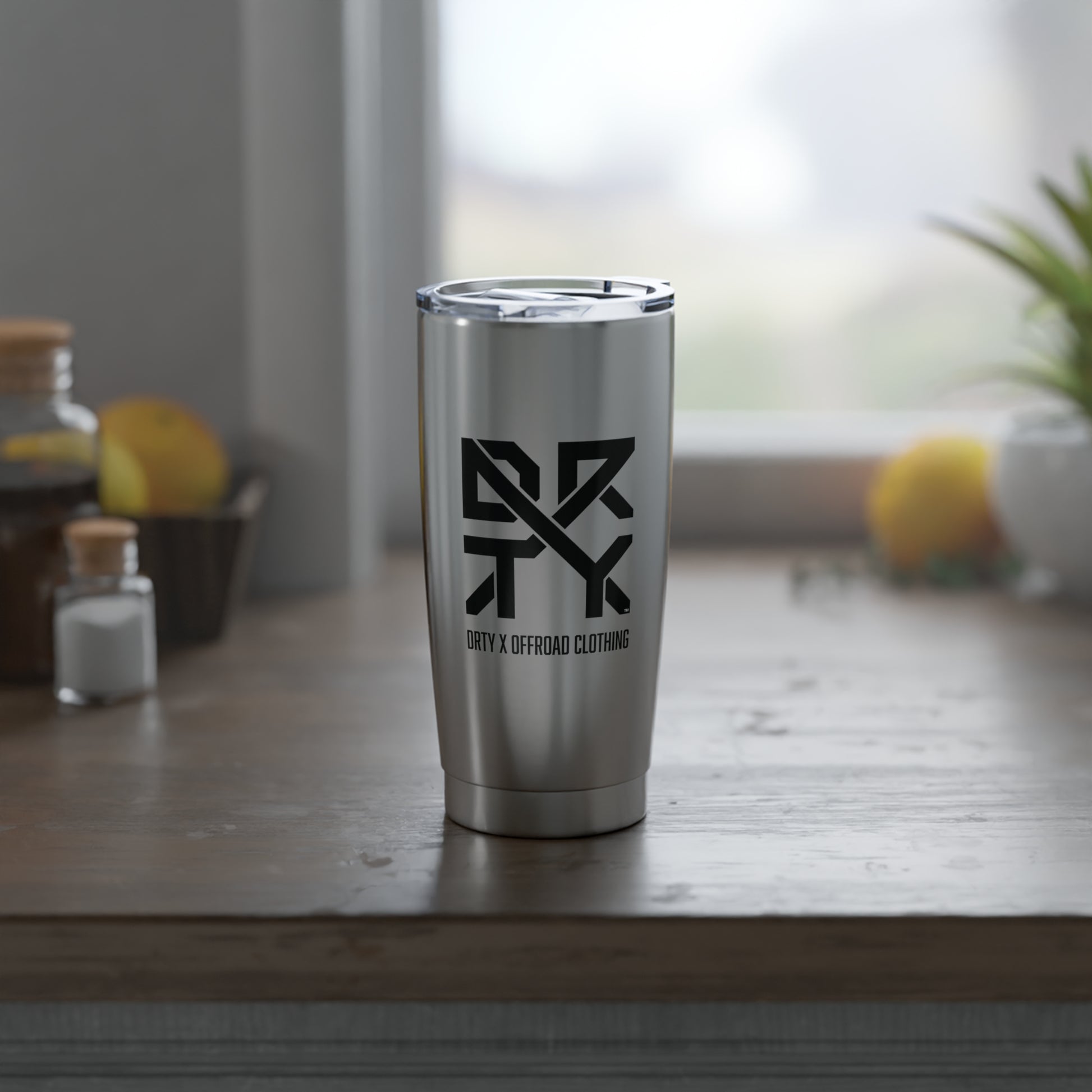 This is a front view of a DRTY X branded stainless steel tumbler on a table.